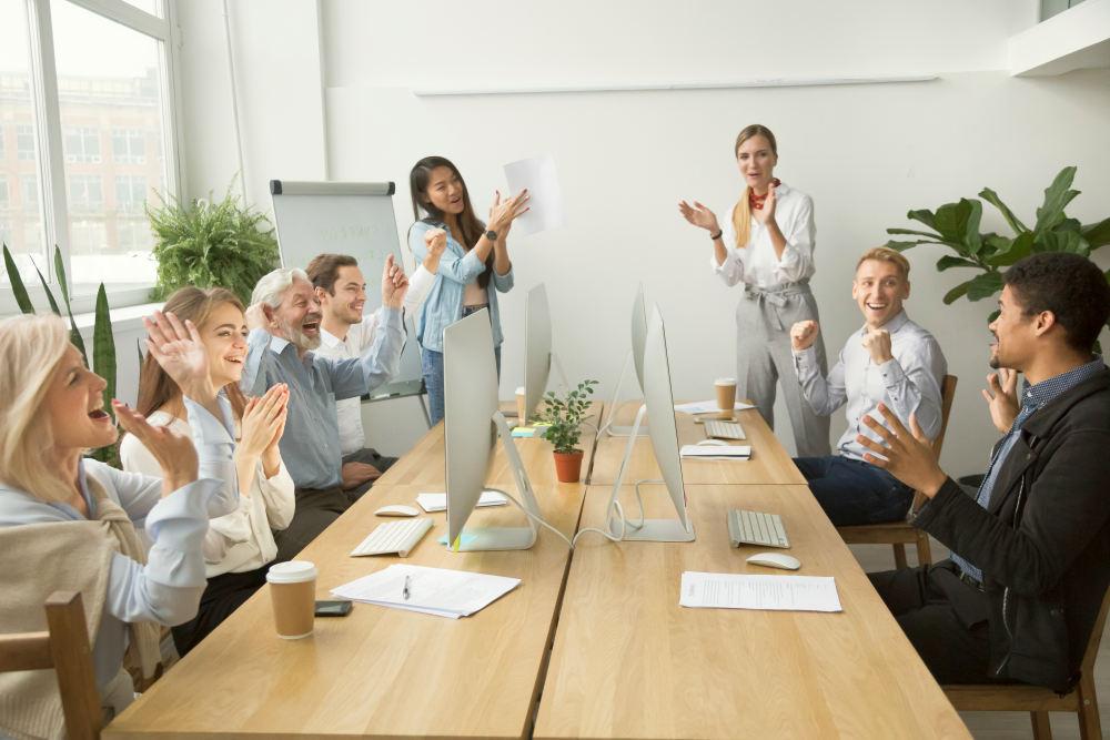 Corporate diverse team colleagues congratulating motivated african coworker with business success | Employee Engagement Ideas During Change With Sharlene Dozois at Cision | effective employee engagement